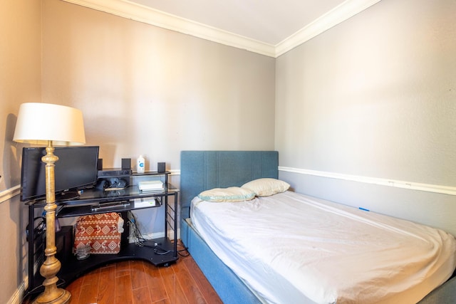 bedroom featuring baseboards, ornamental molding, and wood finished floors