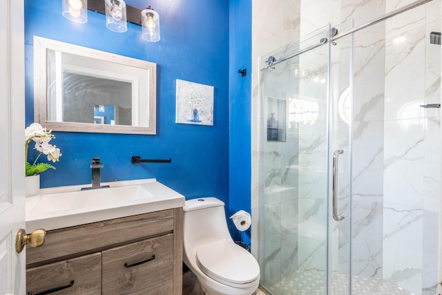 full bath featuring vanity, a marble finish shower, and toilet