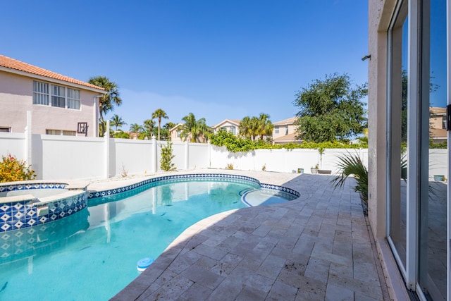 view of swimming pool featuring a patio, a fenced backyard, and a pool with connected hot tub