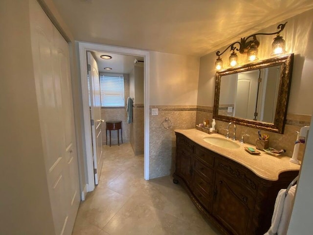 bathroom with tile walls, tile patterned floors, vanity, and a wainscoted wall