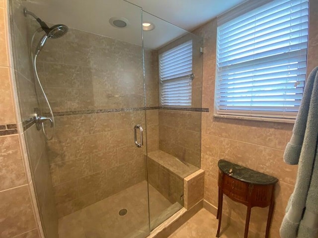 bathroom with a shower stall and tile walls
