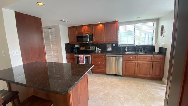 kitchen with stainless steel appliances, visible vents, light tile patterned floors, a sink, and brown cabinetry