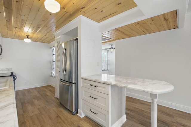 kitchen with freestanding refrigerator, light stone countertops, wooden ceiling, and white cabinetry