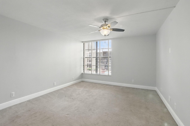 empty room featuring light carpet, a ceiling fan, and baseboards