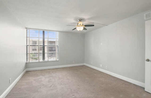 carpeted empty room with ceiling fan, baseboards, and visible vents
