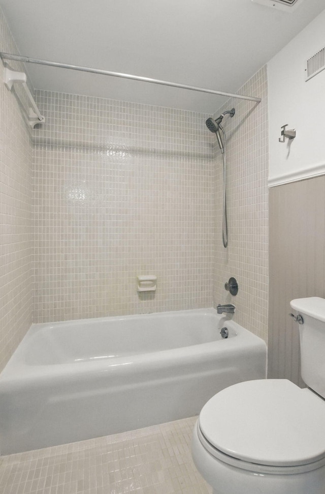bathroom featuring tile patterned floors, a wainscoted wall, bathing tub / shower combination, visible vents, and toilet