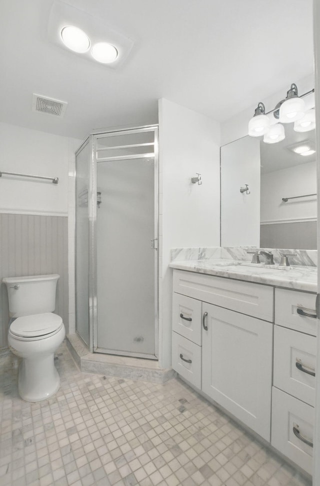 full bath featuring visible vents, toilet, vanity, wainscoting, and a stall shower