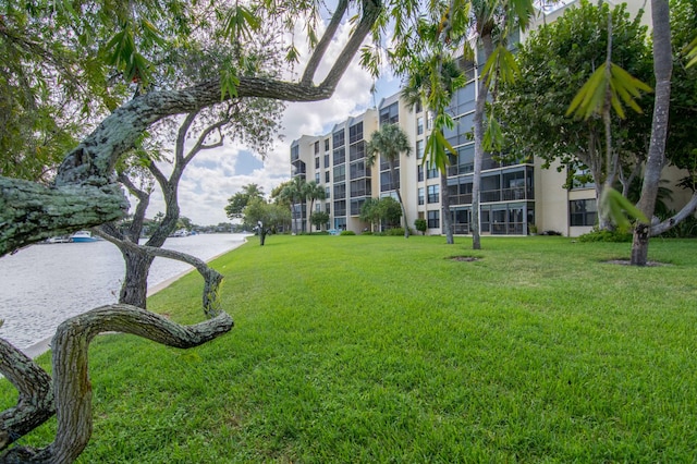 view of property's community with a water view and a lawn