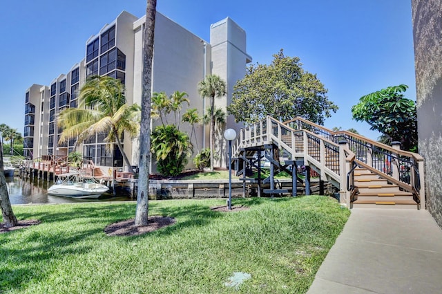 view of home's community featuring a water view, a lawn, and stairs