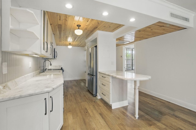 kitchen with open shelves, a sink, wooden ceiling, visible vents, and freestanding refrigerator
