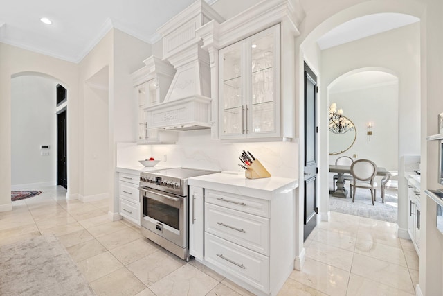 9650 Eden Mnr, Parkland, FL 33076 - kitchen with light countertops, arched walkways, white cabinets, and high end range