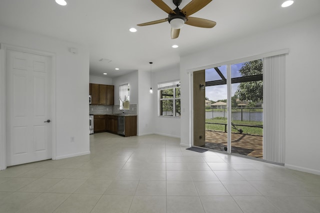 unfurnished living room featuring recessed lighting, baseboards, a sink, and a water view