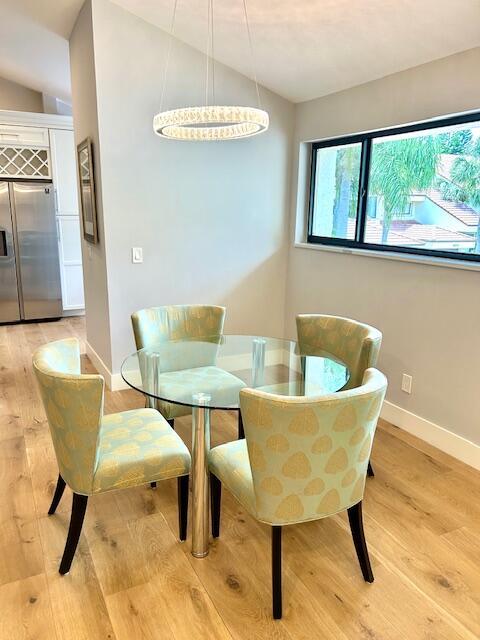 dining space with light wood-style floors, lofted ceiling, and baseboards