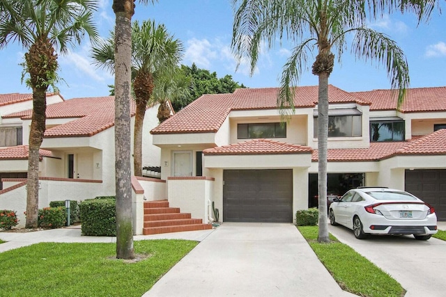 view of front of property featuring an attached garage, concrete driveway, a tiled roof, and stucco siding