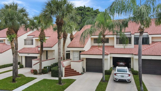 view of front facade with stucco siding, an attached garage, driveway, and a tiled roof