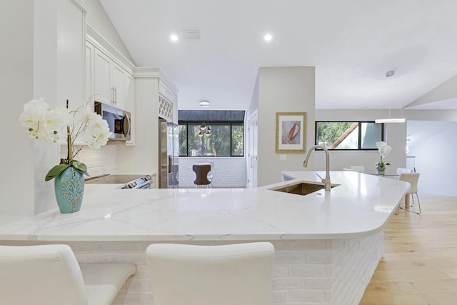 kitchen featuring light stone countertops, a wealth of natural light, stainless steel appliances, and a sink
