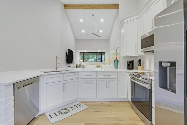 kitchen with high vaulted ceiling, a ceiling fan, a sink, stainless steel appliances, and white cabinetry
