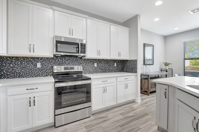 kitchen featuring decorative backsplash, white cabinetry, light countertops, appliances with stainless steel finishes, and recessed lighting