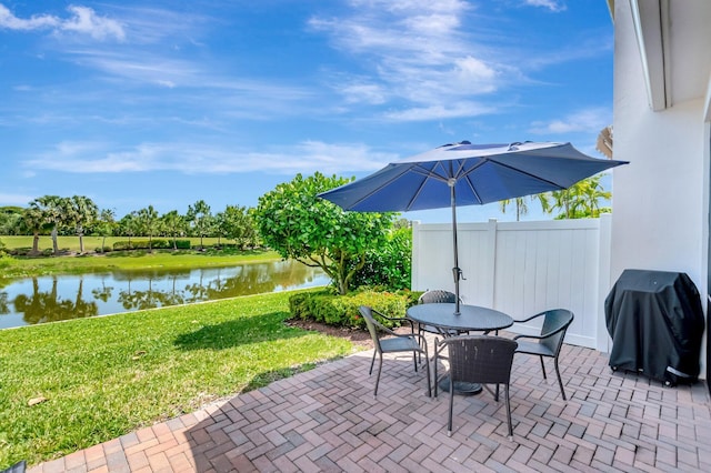 view of patio / terrace featuring grilling area, fence, a water view, and outdoor dining area