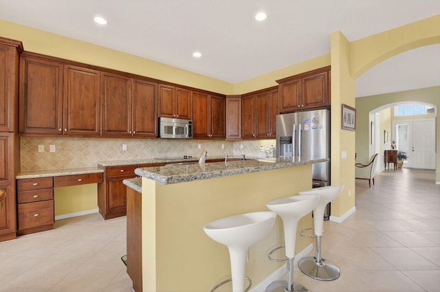 6863 Imperial Beach Cir, Delray Beach, FL 33446 - kitchen with stainless steel appliances, arched walkways, light tile patterned flooring, backsplash, and recessed lighting