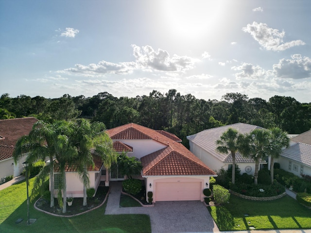 477 NW Blue Lake Dr, Port Saint Lucie, FL 34986 - view of front of property featuring a garage, a tile roof, decorative driveway, a front lawn, and stucco siding
