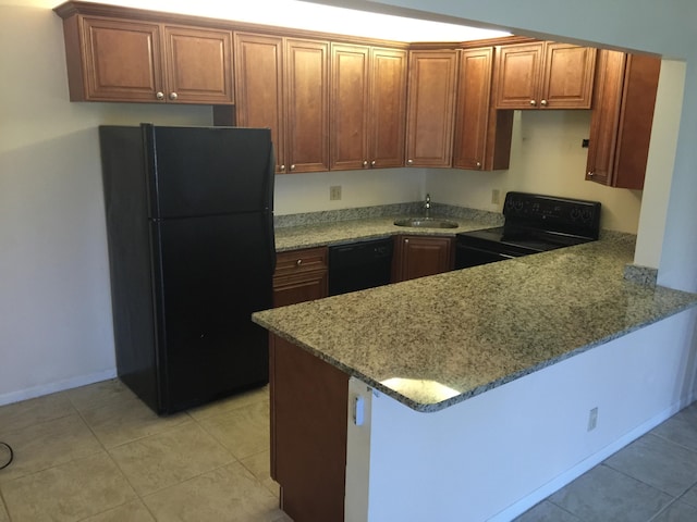 kitchen with light tile patterned floors, a sink, a peninsula, black appliances, and light stone counters