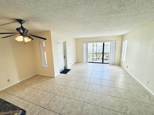 empty room featuring light tile patterned floors, baseboards, a ceiling fan, and a textured ceiling