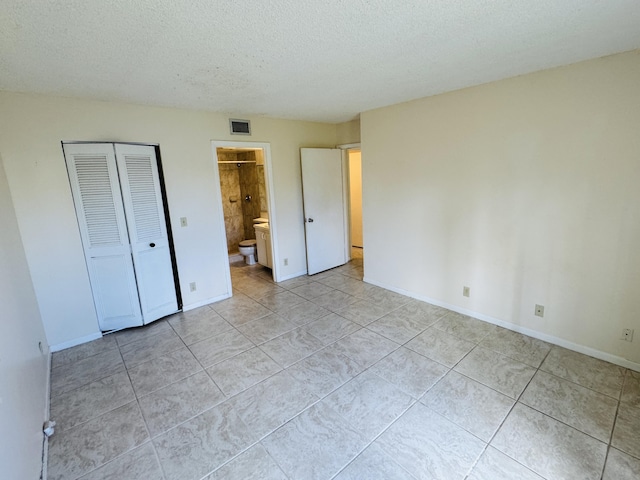 unfurnished bedroom with baseboards, a closet, light tile patterned floors, a textured ceiling, and visible vents