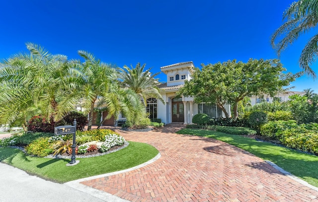 obstructed view of property with a tile roof, stucco siding, and a front lawn
