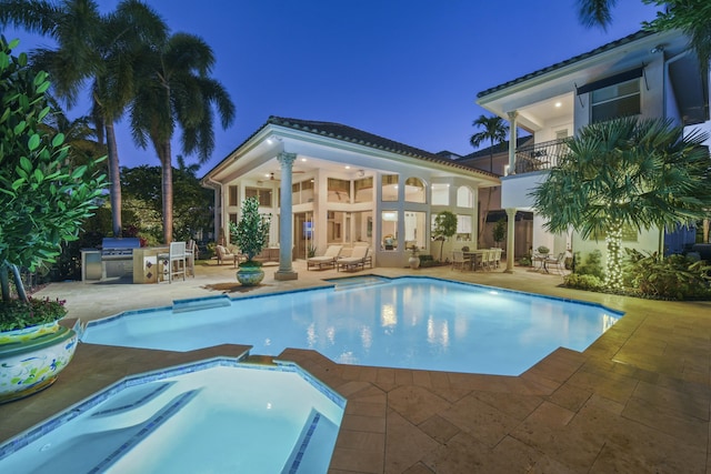 outdoor pool featuring an in ground hot tub, a patio, area for grilling, and an outdoor kitchen