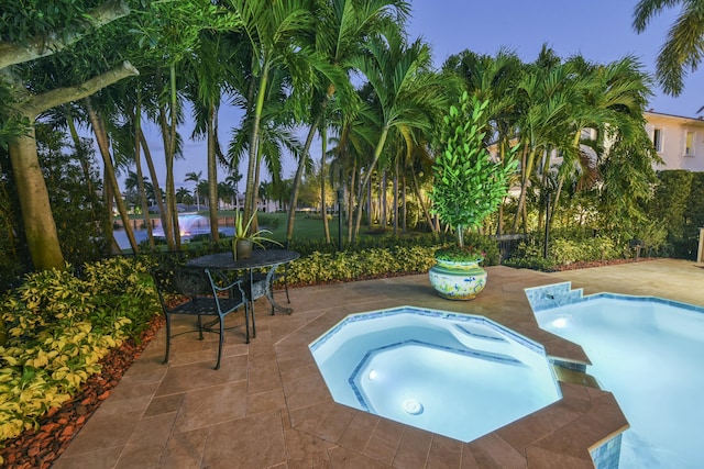 outdoor pool with a patio area and an in ground hot tub