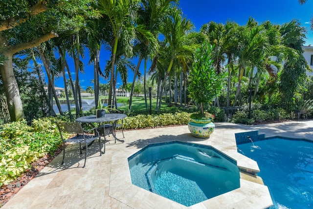 pool featuring a water view, a patio, an in ground hot tub, and fence