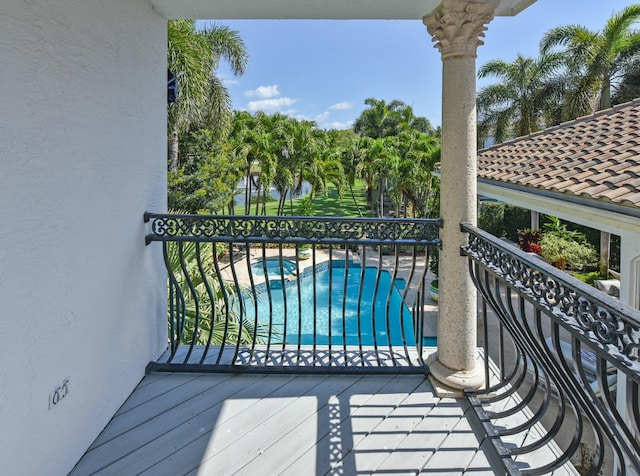 balcony featuring a water view and a pool with connected hot tub