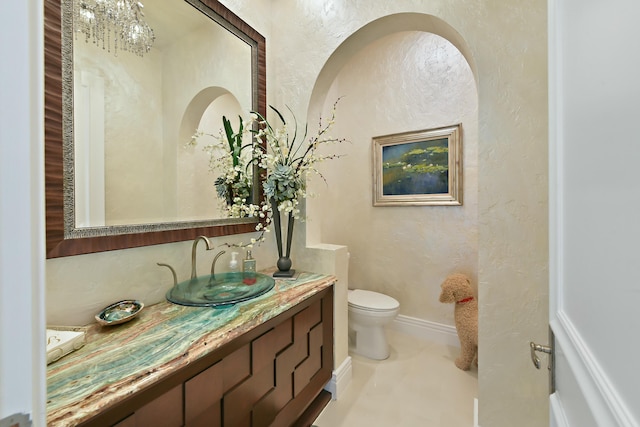 half bathroom featuring a textured wall, vanity, and toilet