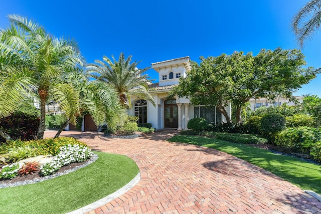 view of front facade with stucco siding, french doors, a front lawn, and a tile roof