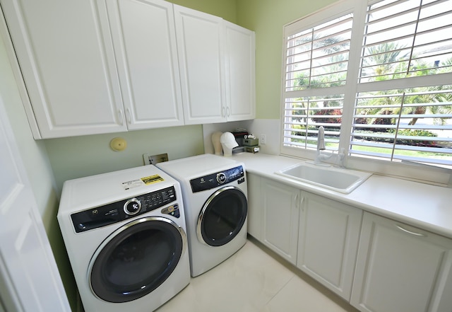 clothes washing area with a sink, cabinet space, and washing machine and dryer