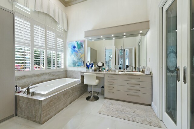 bathroom with a wealth of natural light, vanity, a towering ceiling, and a garden tub