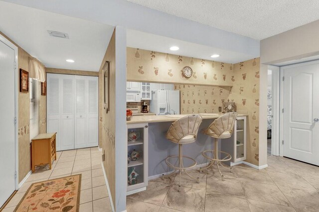 9 Plantation Dr Unit 104, Vero Beach, FL 32966 - interior space with baseboards, wallpapered walls, white appliances, light tile patterned floors, and visible vents
