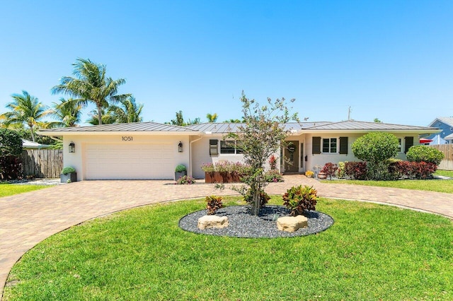 ranch-style house with curved driveway, a standing seam roof, stucco siding, metal roof, and fence
