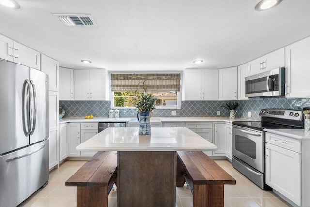kitchen featuring stainless steel appliances, visible vents, decorative backsplash, and light tile patterned flooring