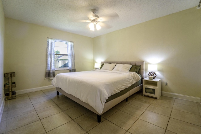 bedroom featuring light tile patterned floors, baseboards, a ceiling fan, and a textured ceiling