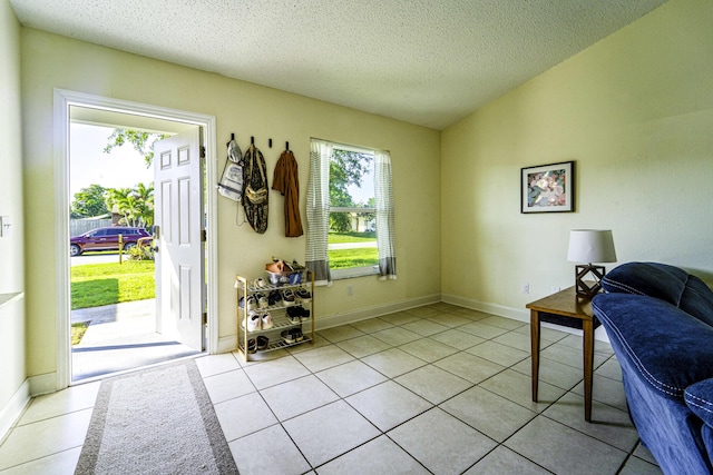 entrance foyer with baseboards, a textured ceiling, and light tile patterned floors