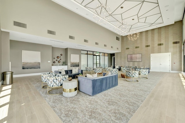 living area with wood finished floors, visible vents, baseboards, and a high ceiling