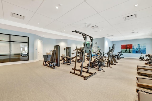 exercise room featuring carpet floors, a paneled ceiling, and baseboards