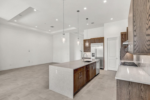 10130 Driftwood Way, Palm Beach Gardens, FL 33412 - kitchen featuring stainless steel appliances, a tray ceiling, a sink, backsplash, and a spacious island
