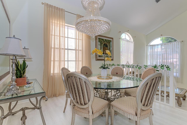 dining space with a chandelier, wood finished floors, and lofted ceiling