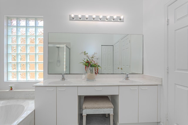 bathroom featuring a stall shower, double vanity, and a bath