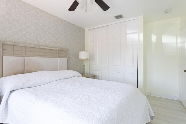 bedroom featuring wallpapered walls, light wood-style floors, baseboards, a closet, and ceiling fan