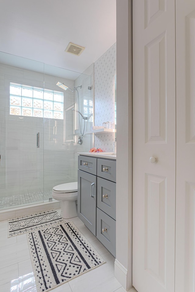 bathroom featuring toilet, a stall shower, tile patterned floors, vanity, and wallpapered walls