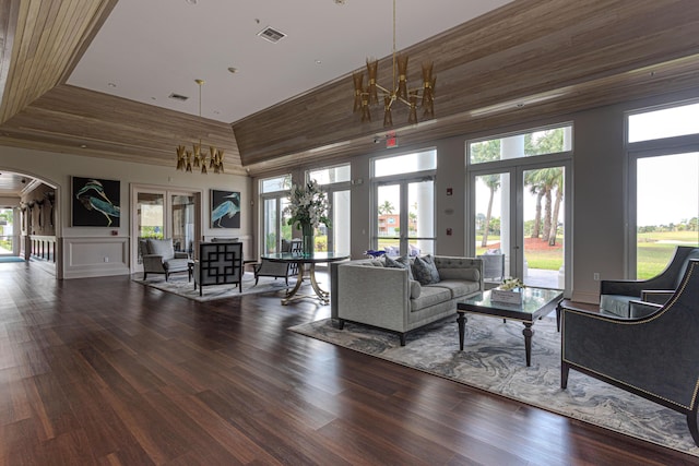 living area with arched walkways, french doors, a high ceiling, healthy amount of natural light, and wood finished floors